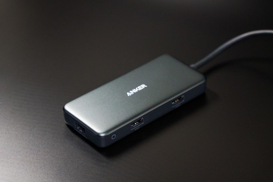 USB-C 허브에 여러 장치가 연결된 모습. 노트북에 연결되어 다양한 포트를 확장하고 있으며, 깔끔한 배경에 퍼플과 옐로우 색감이 강조됩니다.